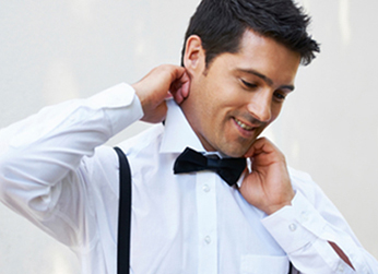 Here's an alt tag for the image: `Man adjusting his bow tie and suspenders.`