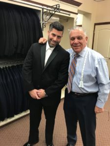 Man in tuxedo with tailor in shop.
