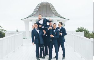 Groomsmen lifting groom; joyful wedding photo.