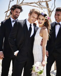 Bride and groom with groomsmen on beach.