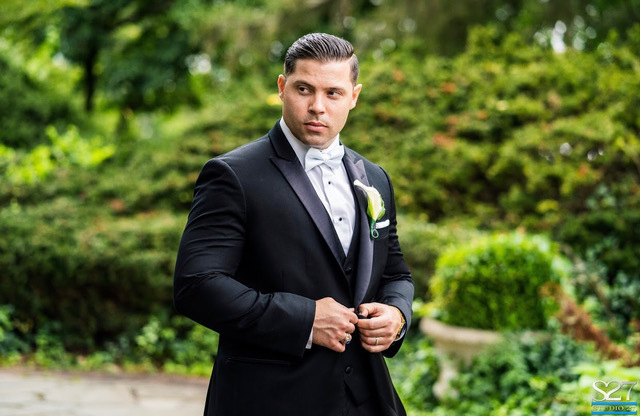 Groom in black tuxedo, outdoors.