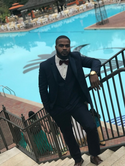 Man in suit by poolside stairs.