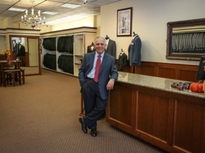 celbrating80thanniversary Man in suit at men's clothing store.
