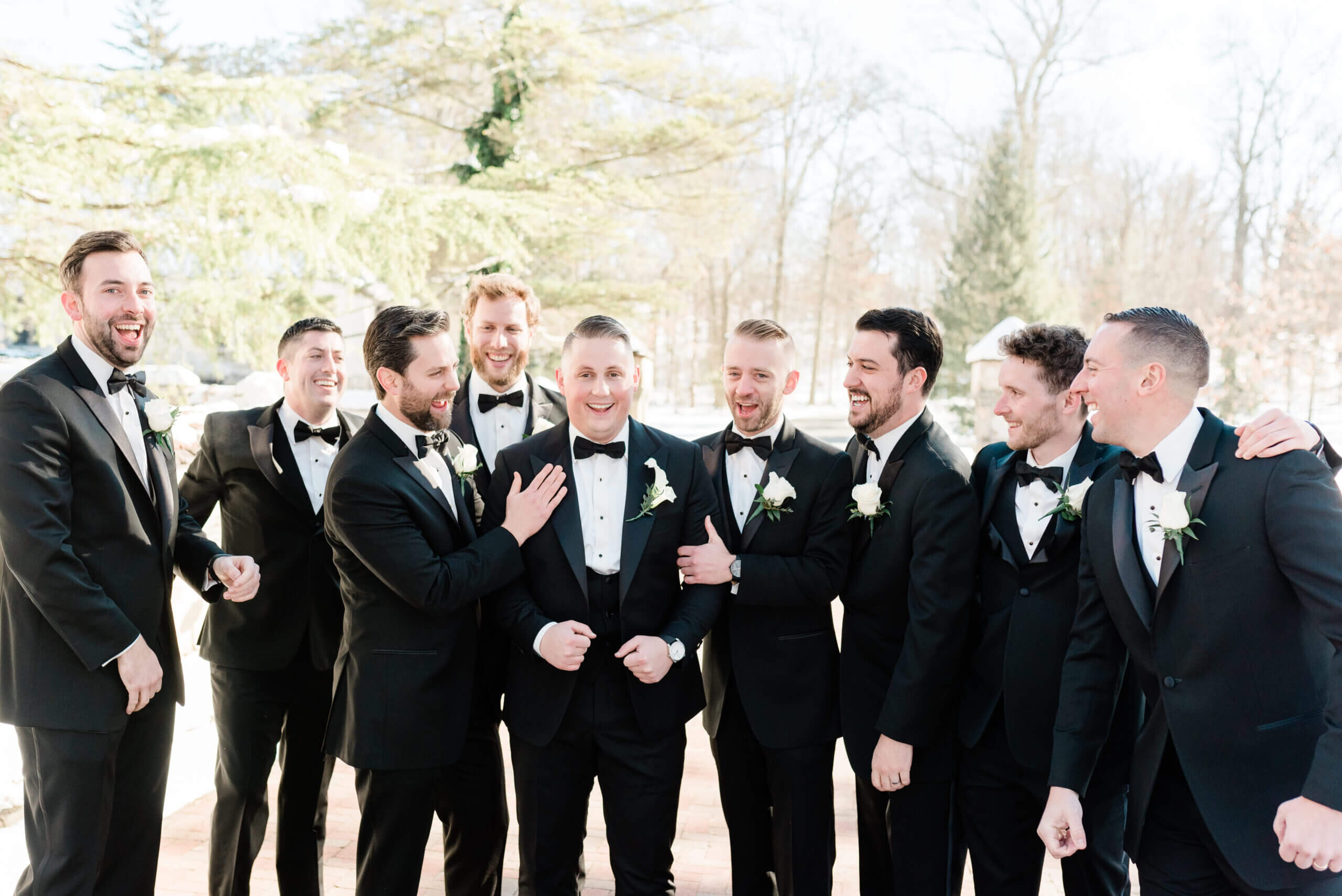 Groom and groomsmen smiling in tuxedos.